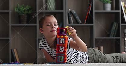 Cute little girl lying on floor play creative magnetic constructor