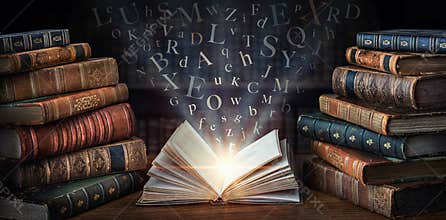 Old book with flying letters and magic light on the background of the bookshelf in the library. Ancient books as a symbol of
