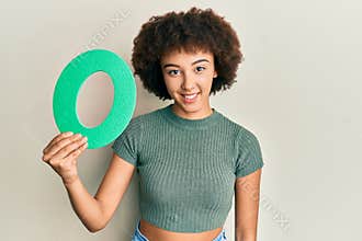 Young hispanic girl holding number zero looking positive and happy standing and smiling with a confident smile showing teeth