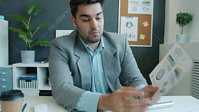 Portrait of employee talking and showing charts during video conference online in office