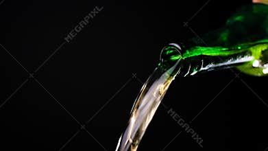 Stream of beer runs through the open green glass bottle in slow motion video, cold beer pours out, liquid flows