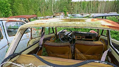 Old car cemetery. Old rusty wrecked car inside and