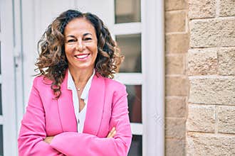Middle age hispanic businesswoman smiling happy standing at the city