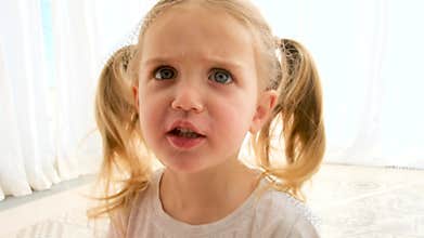 Angry little girl with pigtails in t-shirt shouts to camera