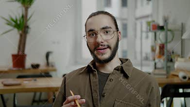 Man with beard and glasses smiles and talks gesticulating