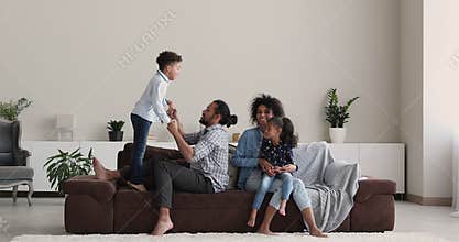 Happy mixed race biracial family playing together in living room.