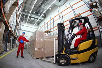 Two workers loading pallets with forklift truck