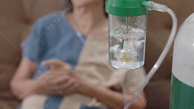 Elderly woman wearing oxygen nasal canula at home