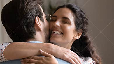 Close up happy Hispanic wife cuddling beloved husband