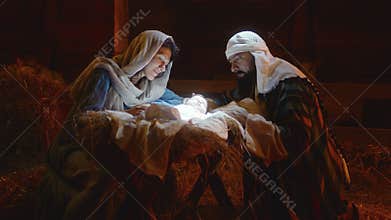 Mary and Joseph caressing baby Jesus in illuminated manger
