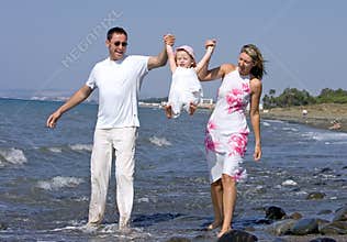 Young family playing with daughter on beach in Spain