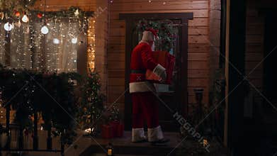General plan Santa Claus carries and delivers a gift in his hands in winter and enters the house with garlands and