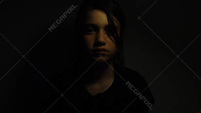 Upset girl emerging from the darkness