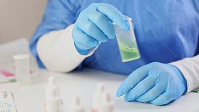 a laboratory assistant in a blue medical suit and gloves conducts water testing, mixes the green reagent with aquarium