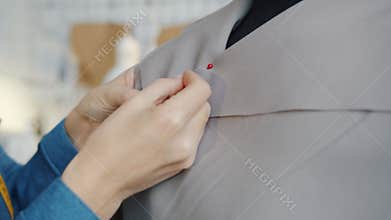 Close-up of female hands sewing new fashionable clothing on tailor's dummy in workshop