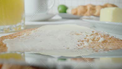 Knife spreading white butter on a toasted piece of crispy toast. Soft butter or cheese smearing on a sandwich close up