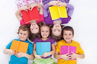 Happy kids laying on the floor holding books
