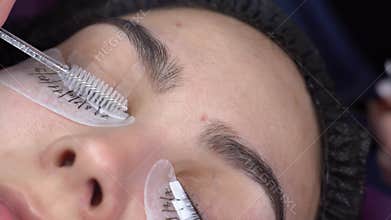 Eyelash extensions in a beauty salon. Ready eyelashes, beautician combing with a special brush, close-up