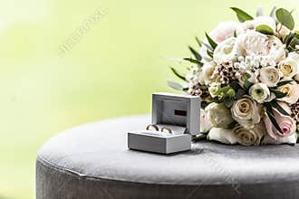 Open box with wedding rings placed next to a bouquette during a wedding
