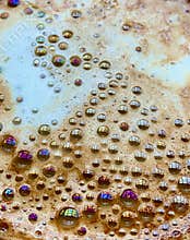 Rainbow of colours in the bubbles on a coffee cup