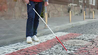A blind man with a cane crosses the road