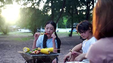 Happy Asian family having barbecue together. Cooking grilled bbq for dinner during camping on summer beach