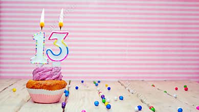 Muffin with cream and number 13 for a birthday on a pink background, copy space, holiday background. Happy birthday greetings