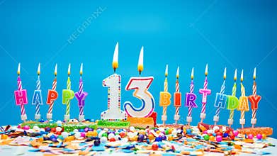 Happy birthday candle letters with the number thirteen on a beautiful blue background. Copy space Happy birthday greetings for 13