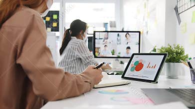 Asia businesspeople wear face mask using desktop talk to colleagues discussing brainstorm about plan in video call meeting in new