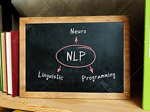 Concept about NLP Neuro Linguistic Programming . Bookshelf with multicolor books and chalkboard