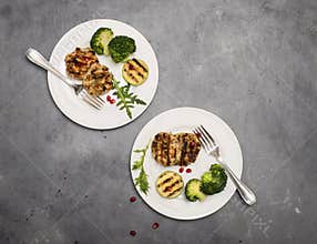 Turkey or chicken cutlets meatballs zucchini and broccoli in white plates on a grey background  top view. Healthy balanced food