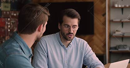 Concentrated skilled young 35s employee communicating with colleague.