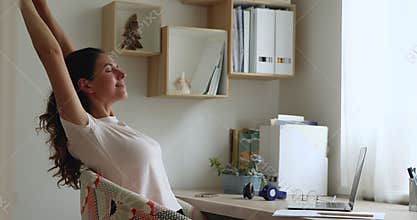 Smiling young woman relaxing after finishing computer work.