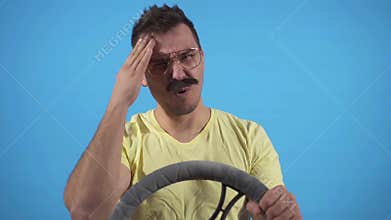 Funny man gets into an accident and bangs his head on the steering wheel on a blue background slow mo, isolate