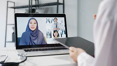 Young Asia female doctor in white medical uniform with stethoscope using computer laptop talking video conference call with