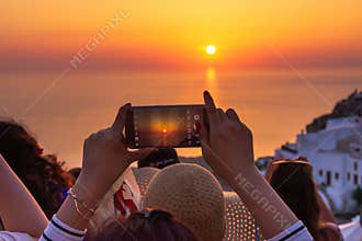 A tourist taking picture of sunset in Santorini, Greece. wish list for 2021.