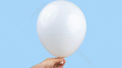 White balloon being blown up against blue background