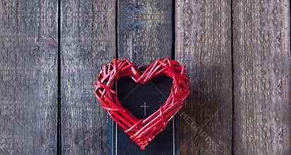 Bible book on a wooden table. Red heart. Cross on holy bible