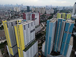Aerial drone view of modern apartment building in Jakarta central business district with Jakarta cityscape and noise cloud.