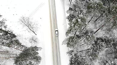 Classic gray car driving through the white winter snowy forest on country road. Top view. Winter or alpine road in the