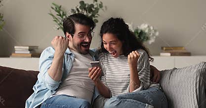 Sincere young family couple celebrating online win.
