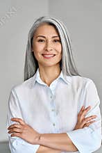 Vertical portrait of mature 50 years Asian business woman on grey background.