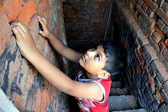 Dramatic look of a child. Portrait of a child. A child is trying to climb up on the wall.