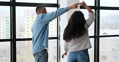 Happy couple dancing and having fun in front on window
