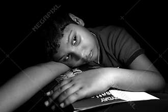 Cute boy portrait. Child laid on books during his study time and thinking something.