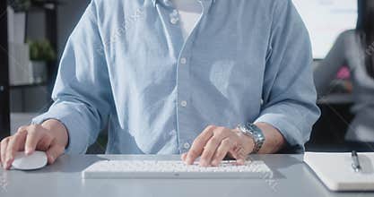 Asian man using desktop computer in home office with business partner, close up hand typing keyboard and mouse click