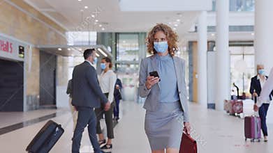 Businesswoman wearing face mask and checking her phone at airport
