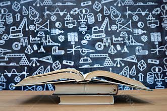 Blackboard with hand-drawn math-related icons. Books stacked on the desk. Education concept