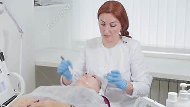 Professional beautician woman applies a mask to the face of a client in a beauty parlor.