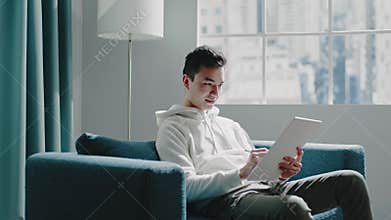 Student guy in white hoodie writes home assignment on tablet